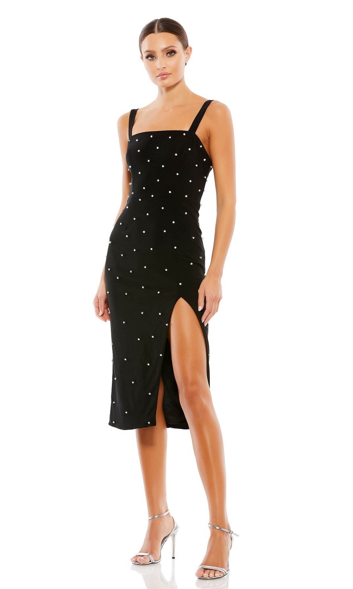 A woman wears the Mac Duggal Short Wedding Guest Dress 70211—a black, knee-length, pearl square neck dress with white dots, thigh-high slit, and silver heels—perfect for any elegant party or special occasion.